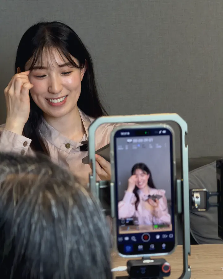 縦向きに固定したスマートフォンの画面に、目の前の出演者と同じ構図が映っている撮影の様子
